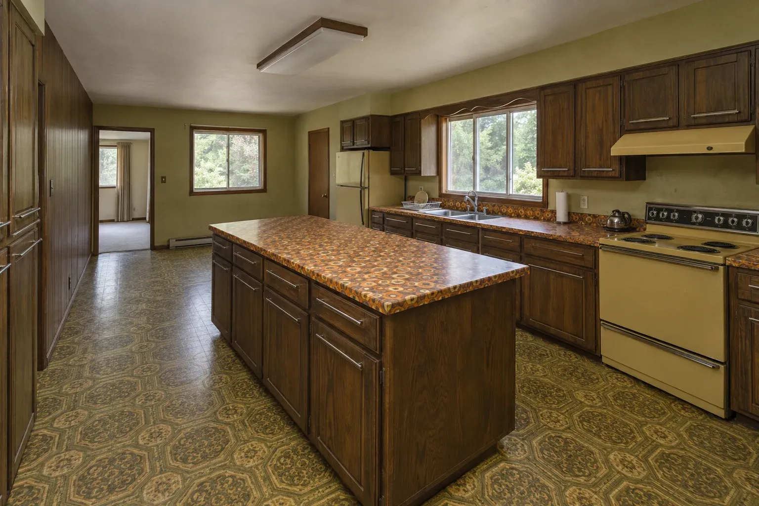 Dark oak kitchen with a patterned vinyl floor and dated wall cabinets before remodeling